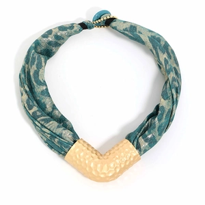 Macro detail of blue leopard print fabric and hammered gold V-shape pendant necklace