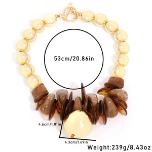 Chunky necklace with yellow pearl beads, brown resin charms, and gold ball pendant