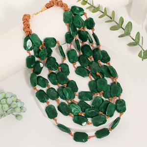 Gros plan du collier multicouche en perles acryliques vertes avec cordelette tissée