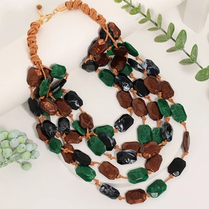 Détail macro d'un collier multicouche en perles acryliques facettées vert forêt