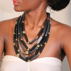 Collana boho multistrato con perline di legno nere e sfere dorate indossata da modella