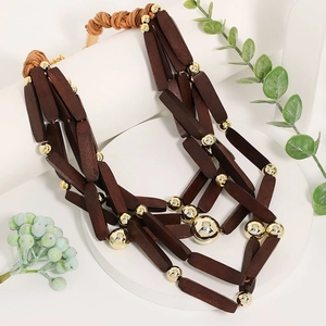 Collana bohémien multistrato con barre di legno scuro e perline dorate su base bianca