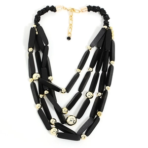 Dettaglio di una collana boho multistrato con perline nere opache e sfere dorate lucide