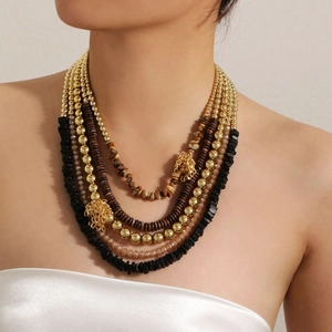 Detail of bohemian layered necklace with golden lion head and mixed beads on a model