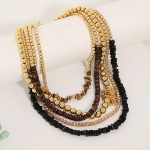 Macro detail of multi-layered bohemian beaded necklace with gold and earth-toned beads