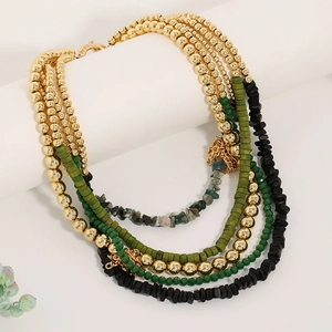 Detail of multi-layer beaded necklace with green stones and gold beads on white stand