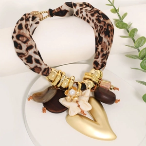 Boho leopard print necklace with large heart and flower charms on a display stand