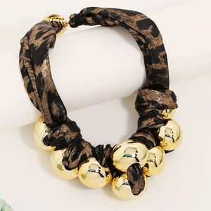 Statement leopard print fabric necklace with bold golden beads on a display stand