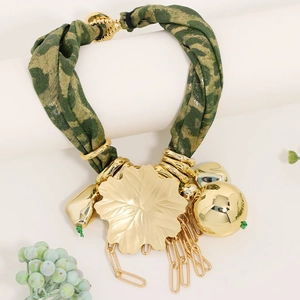 Detailed close-up of golden hollow leaf pendant and leopard fabric texture necklace