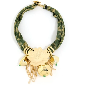 Macro view of gold maple leaf pendant and green fabric necklace with bell charms