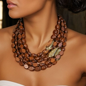 Detail of multi-layer wood beads and gold teardrop pendants on a bohemian necklace