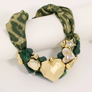 Detail of leopard print ribbon necklace featuring a large faceted gold heart pendant
