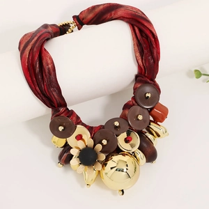 Macro shot of dark red ribbon necklace with golden petals and metallic pendant drops