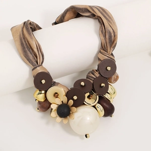 Macro detail of ribbon necklace with tiger print, wood bead, pearl and flower pendant