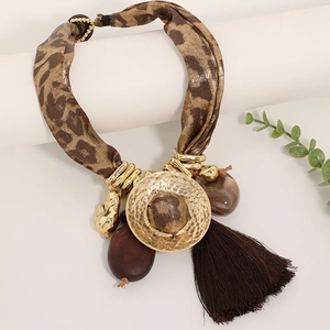 Détail du collier imprimé léopard avec disque doré et long gland marron foncé