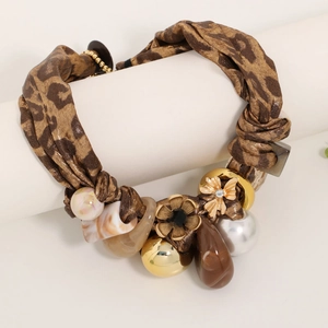 Leopard print fabric necklace with faux pearls and floral charms on a display stand