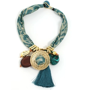 Détail du collier en tissu léopard avec disque doré martelé et gland en soie sarcelle