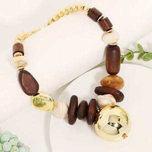 Macro shot of boho necklace with large gold sphere, wood beads and cream pearls