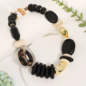 Handmade beaded necklace with leopard print pendant and gold accents on a white stand