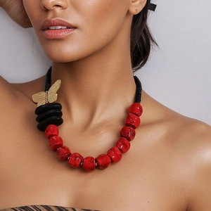 Fashion chunky necklace with red beads, black discs and gold butterfly charm on model
