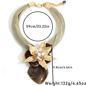 Détail du collier plastron avec chaîne en maille dorée et pendentif fleur en résine ambre