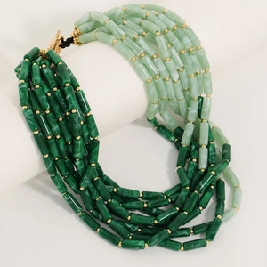 Bohemian multi-layer necklace with green gradient beads and gold spacers on a white stand