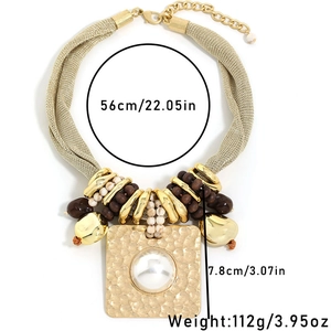 Détail du collier chaîne dorée avec pendentif carré martelé et incrustation perle