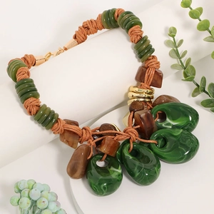 Detailed view of bohemian resin bead necklace with green and brown stones on white display