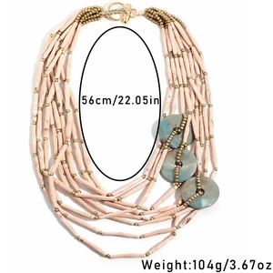 Detail of multi-layer beaded necklace with green marble accents and golden T-bar clasp