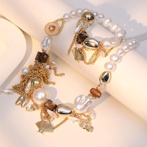 Bohemian baroque pearl necklace with gold tassels and vintage pendants on white stand