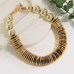 Modern golden CCB disc and bead necklace with T-bar clasp on a white platform