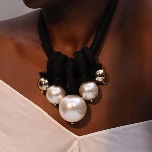 Statement oversized pearl necklace with gold beads and bold black braided cord knot
