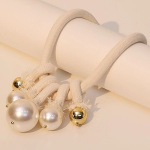Minimalist beige cord necklace with white faux pearls and gold beads on white pedestal