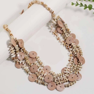 Close-up of layered bohemian necklace with shell fragments and smooth pink disc beads