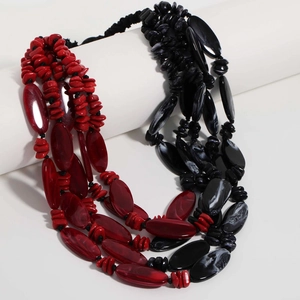 Detail of multilayer acrylic beaded necklace featuring red and black marbled stones