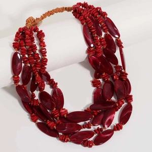 Close-up of multi-layer red resin beads and marble-textured stones on woven cord