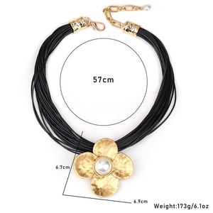 Detailed view of multilayer wax cord necklace featuring a large gold flower with pearl