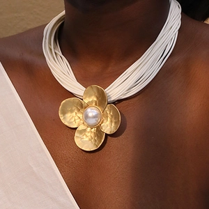 Statement gold flower necklace with pearl accent and multi-strand white cord on model