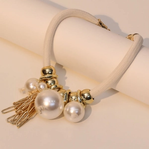 Bohemian style rope necklace featuring faux pearls and gold paperclip tassels on a display