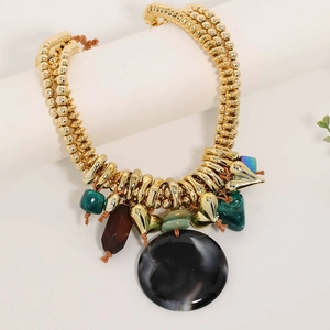 Detail of bohemian gold beaded necklace with black round pendant and green faux gems