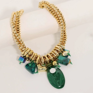 Detailed shot of multi-layered gold beaded necklace with green malachite-style charms
