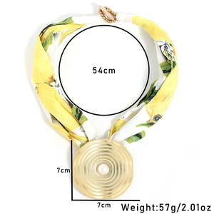 Macro shot of 7cm gold medallion pendant and yellow floral silk scarf necklace