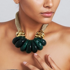 Artistic gold mesh necklace with dark green teardrop resin pendants on a model