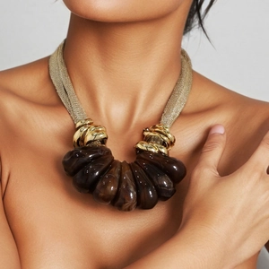 Statement necklace featuring golden mesh chain and amber resin teardrop pendants on a model