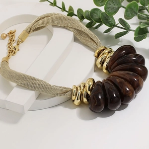 Macro detail of amber resin beads and braided gold mesh chain on teardrop necklace