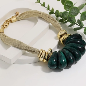 Detailed close-up of chunky gold woven mesh necklace with dark green resin pendants