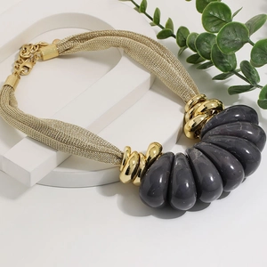 Detailed close-up of woven gold metal mesh chain with grey teardrop pendant accents