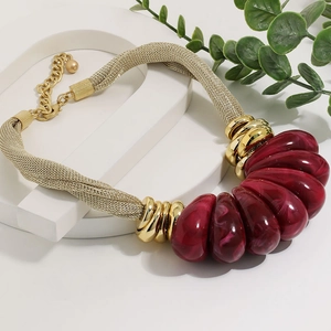 Detailed view of chunky gold mesh necklace with marbled burgundy resin beads