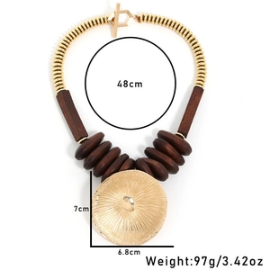 Macro shot of ethnic wooden beads and a large gold lotus-shaped leaf pendant