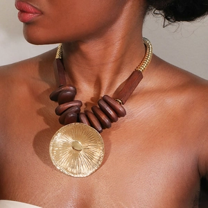 Ethnic wood bead necklace with a large gold lotus pendant on a dark-skinned model